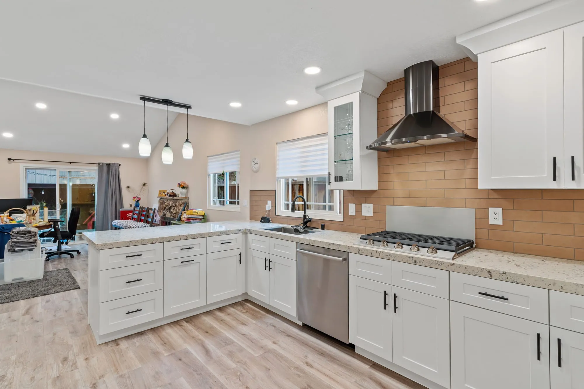 The same kitchen after remodel, white shaker cabinetry and speckled granite counters
