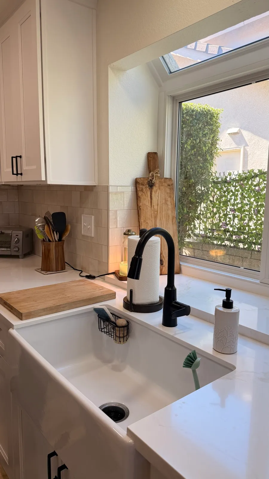 Farmhouse apron sink with a gooseneck faucet set below the kitchen window