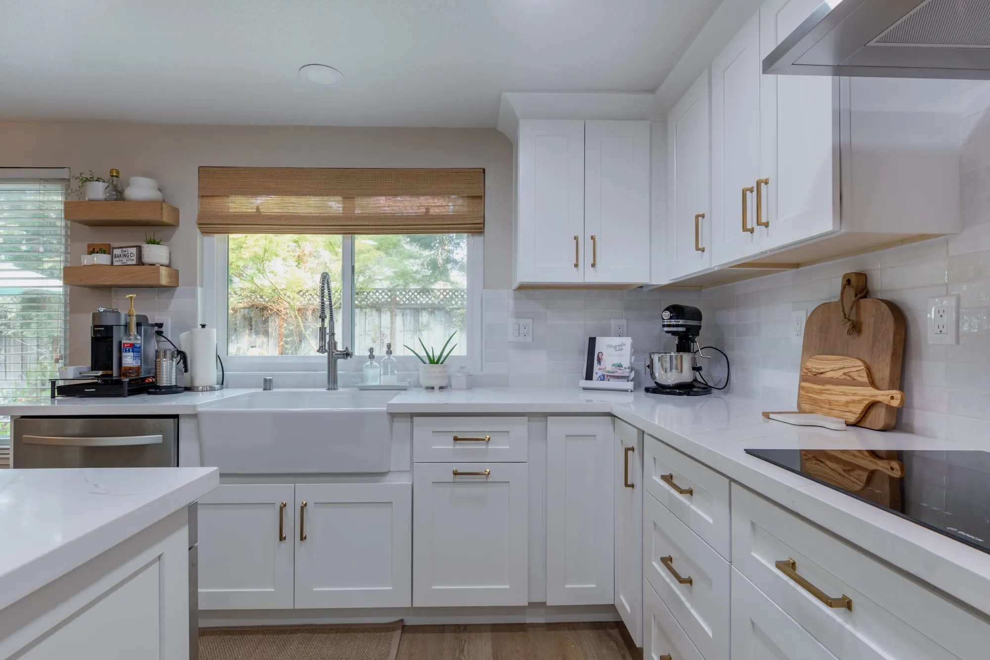 White apron sink under the window with a woven shade above it