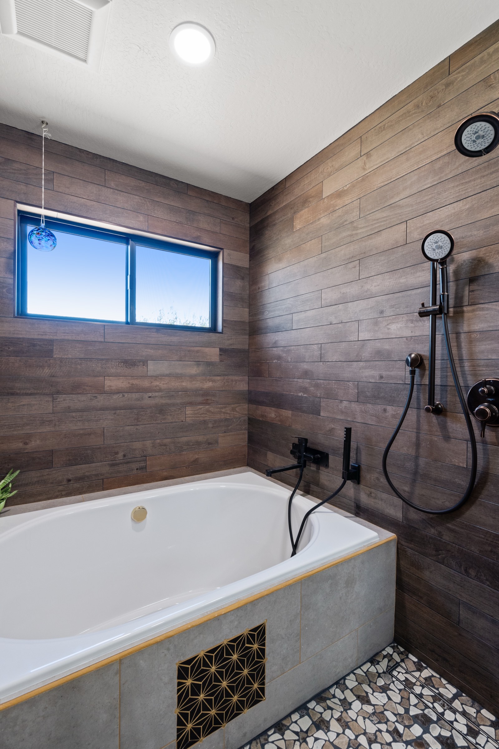 Bathroom with wood-plank tile shower surround, drop-in tub, and matte black fixtures