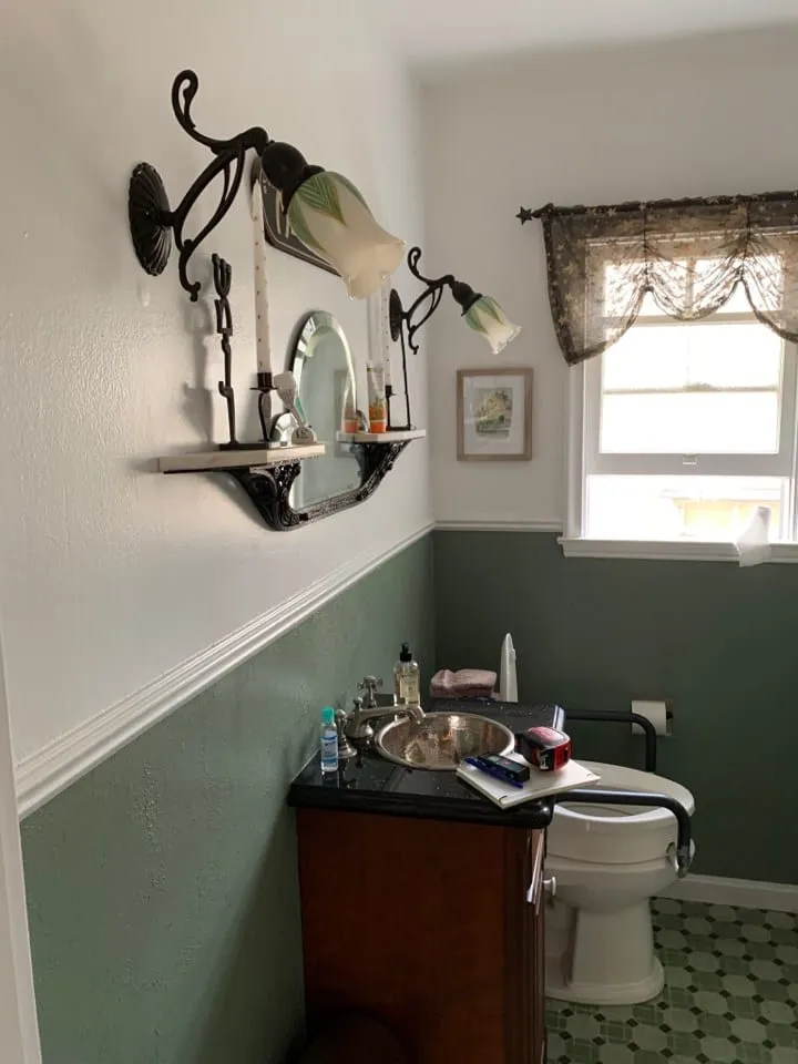 Original bathroom before remodel, dark vanity below a green painted wall