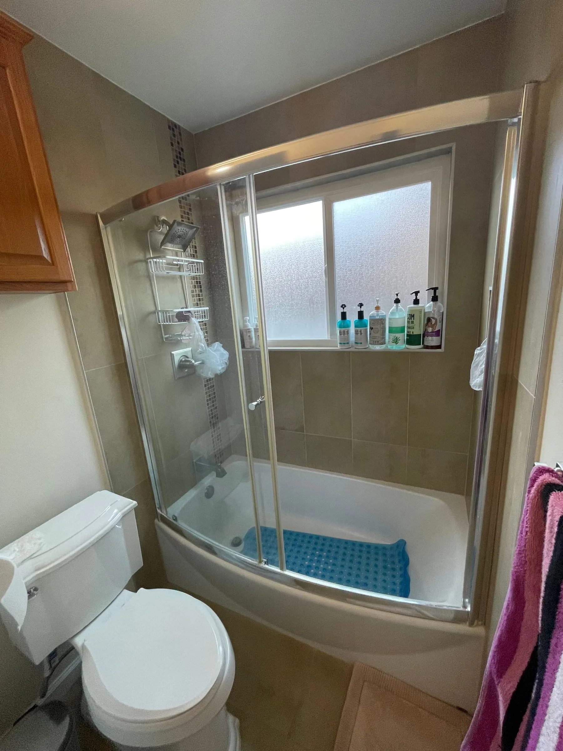 Original bathroom before remodel, framed sliding shower door over a built-in tub