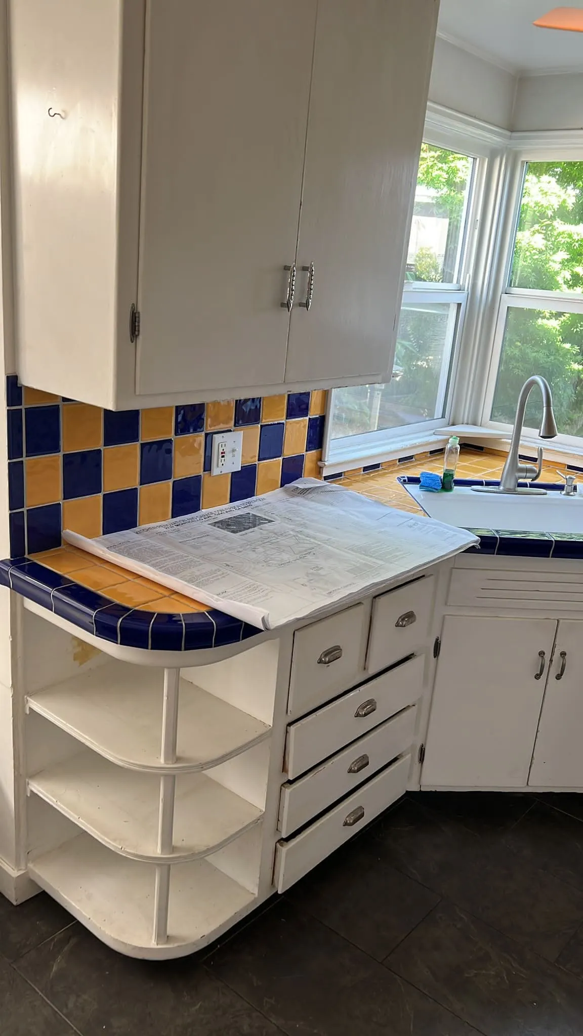 Original kitchen before remodel, blue and yellow tiled counters with white cabinets