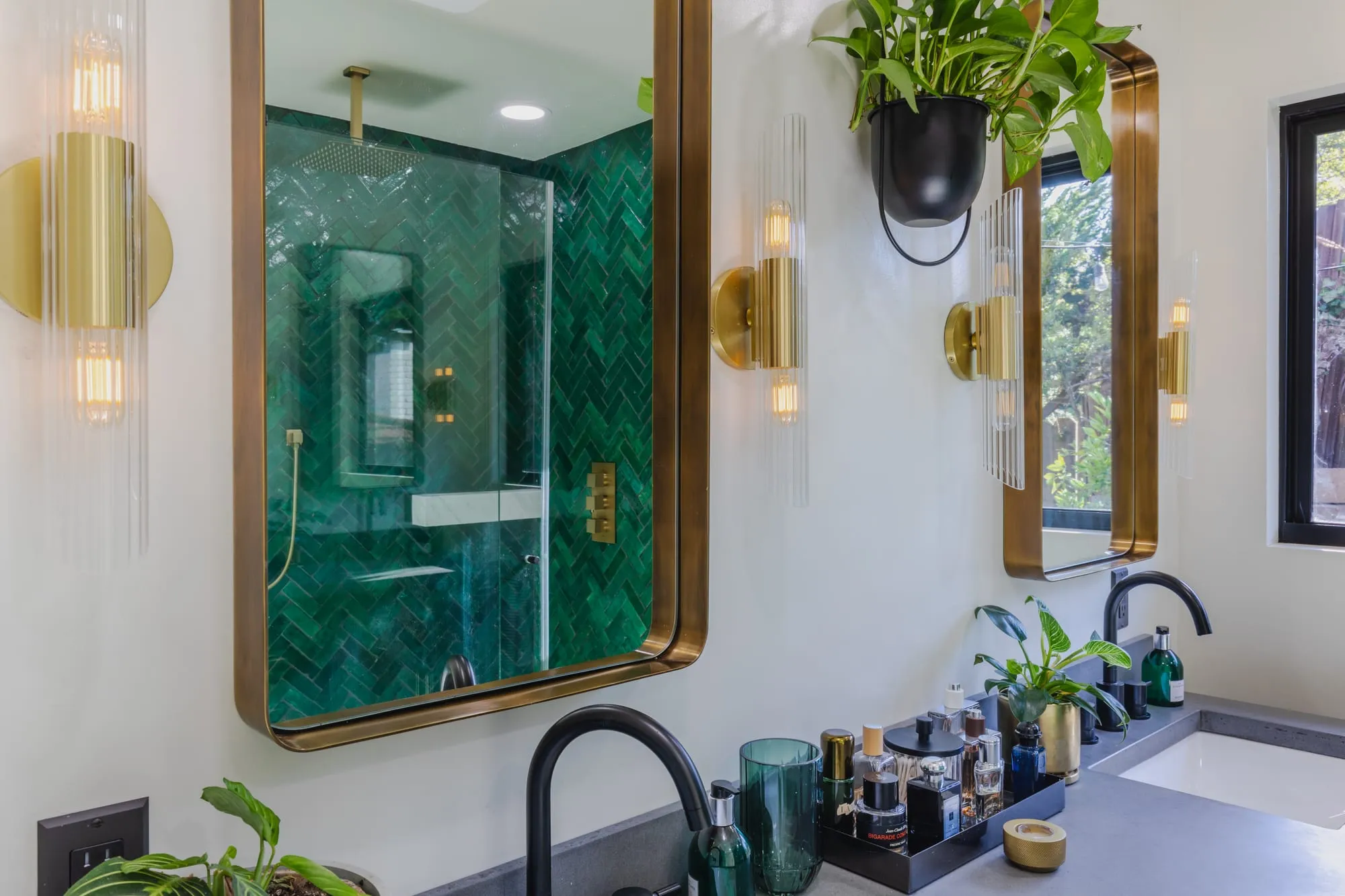 Two brass-framed mirrors between fluted brass wall sconces above the vanity