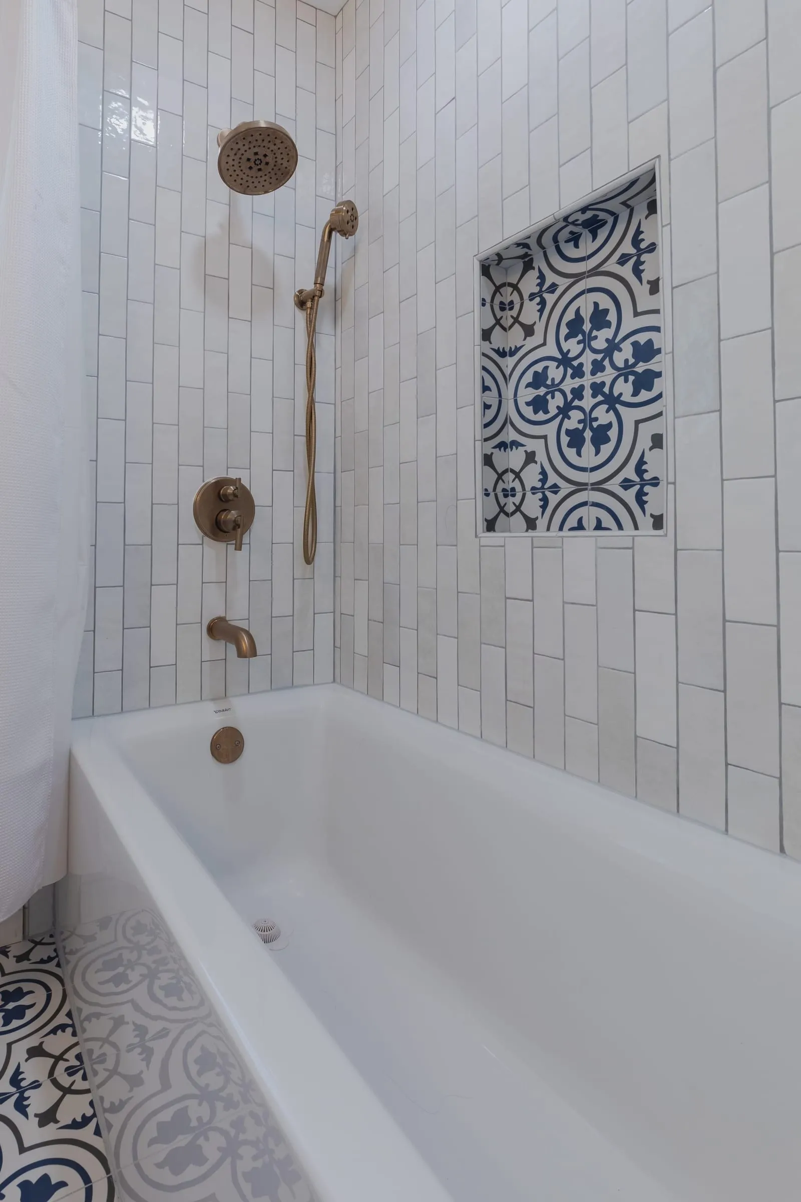 Brushed brass tub filler against the stacked tile