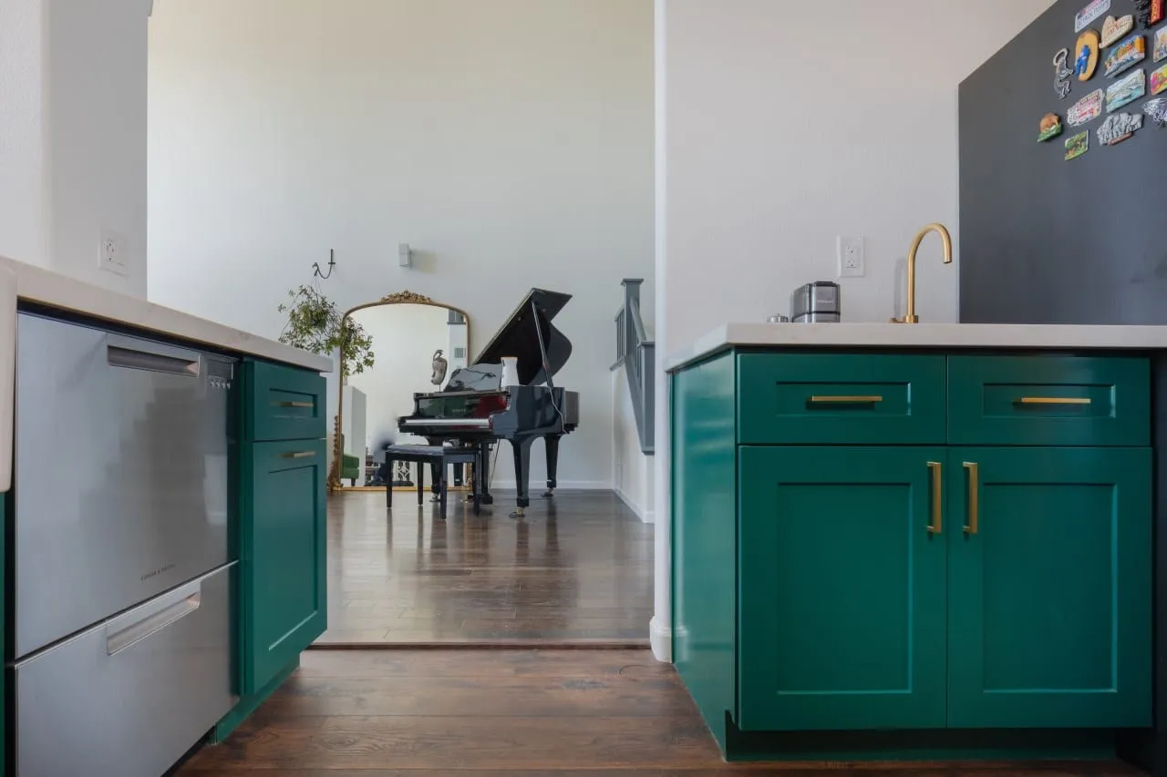 Emerald island end with long brass pulls beside a stainless dishwasher
