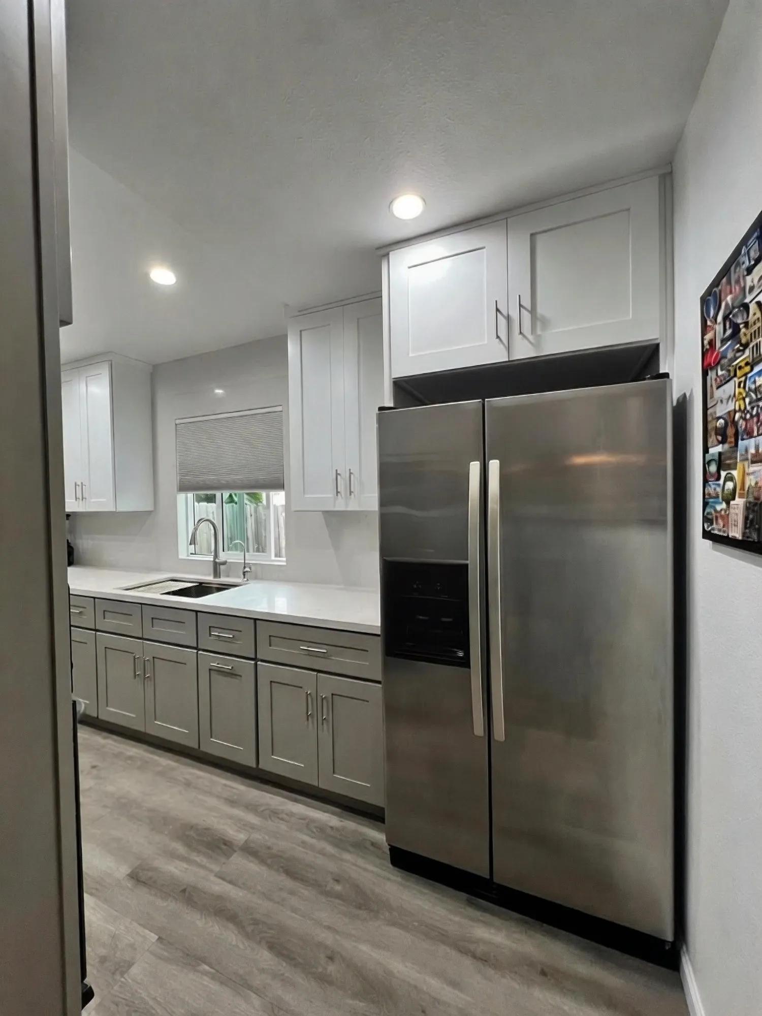 Stainless fridge between tall cabinets at the end of the run