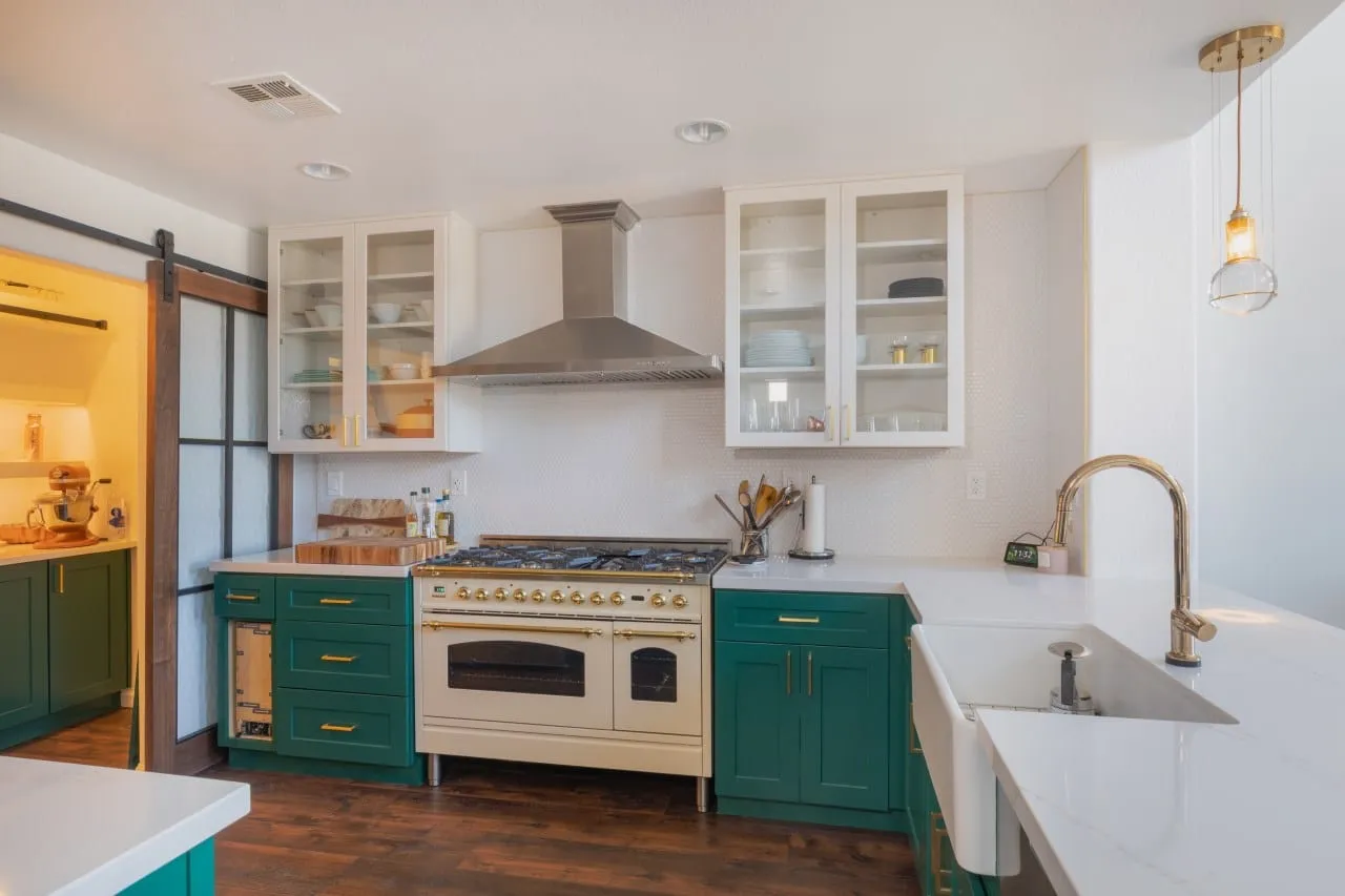 White glass-fronted upper cabinets above the emerald run and the cream range