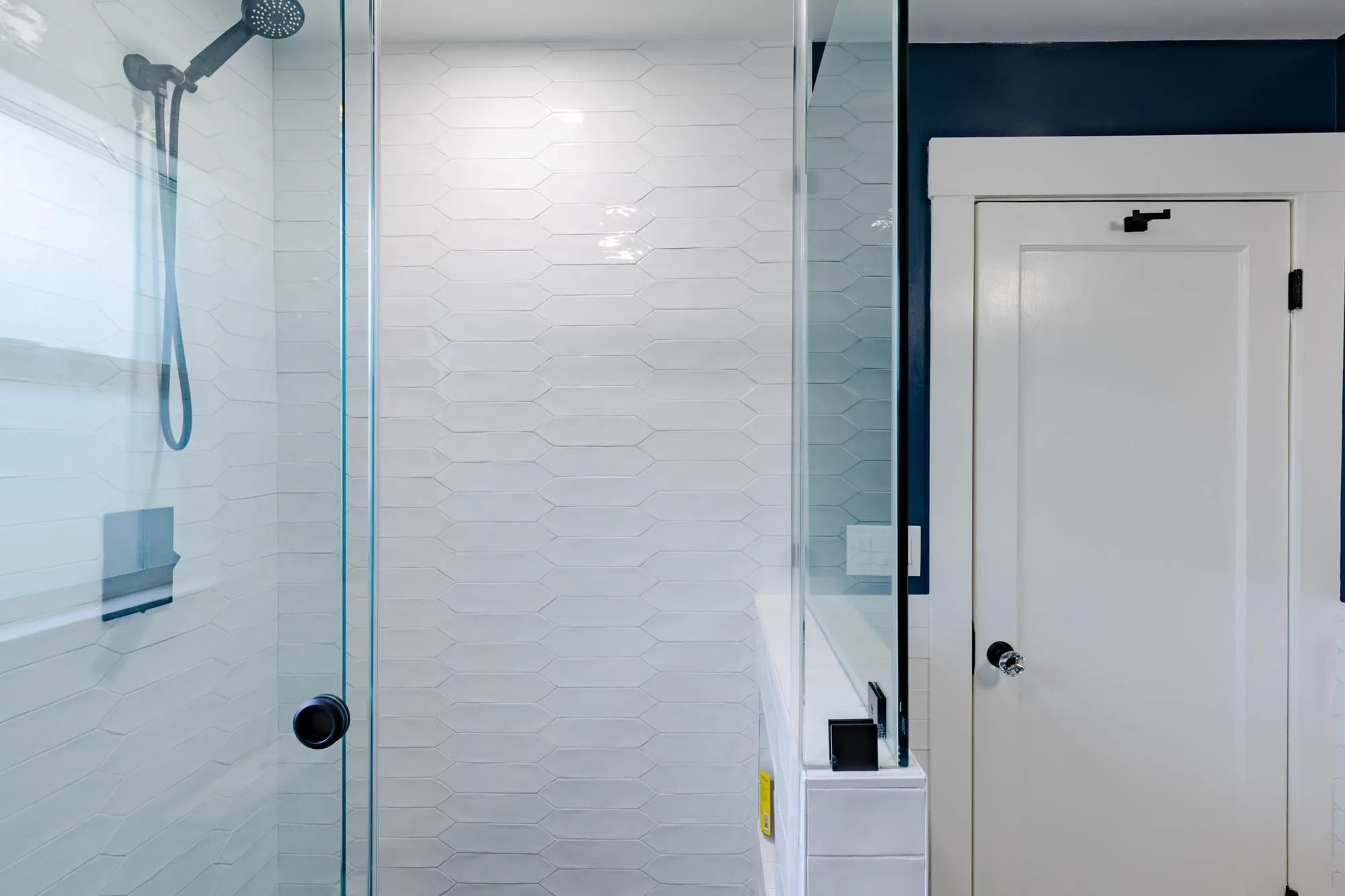 Frameless glass shower door with a matte black handle