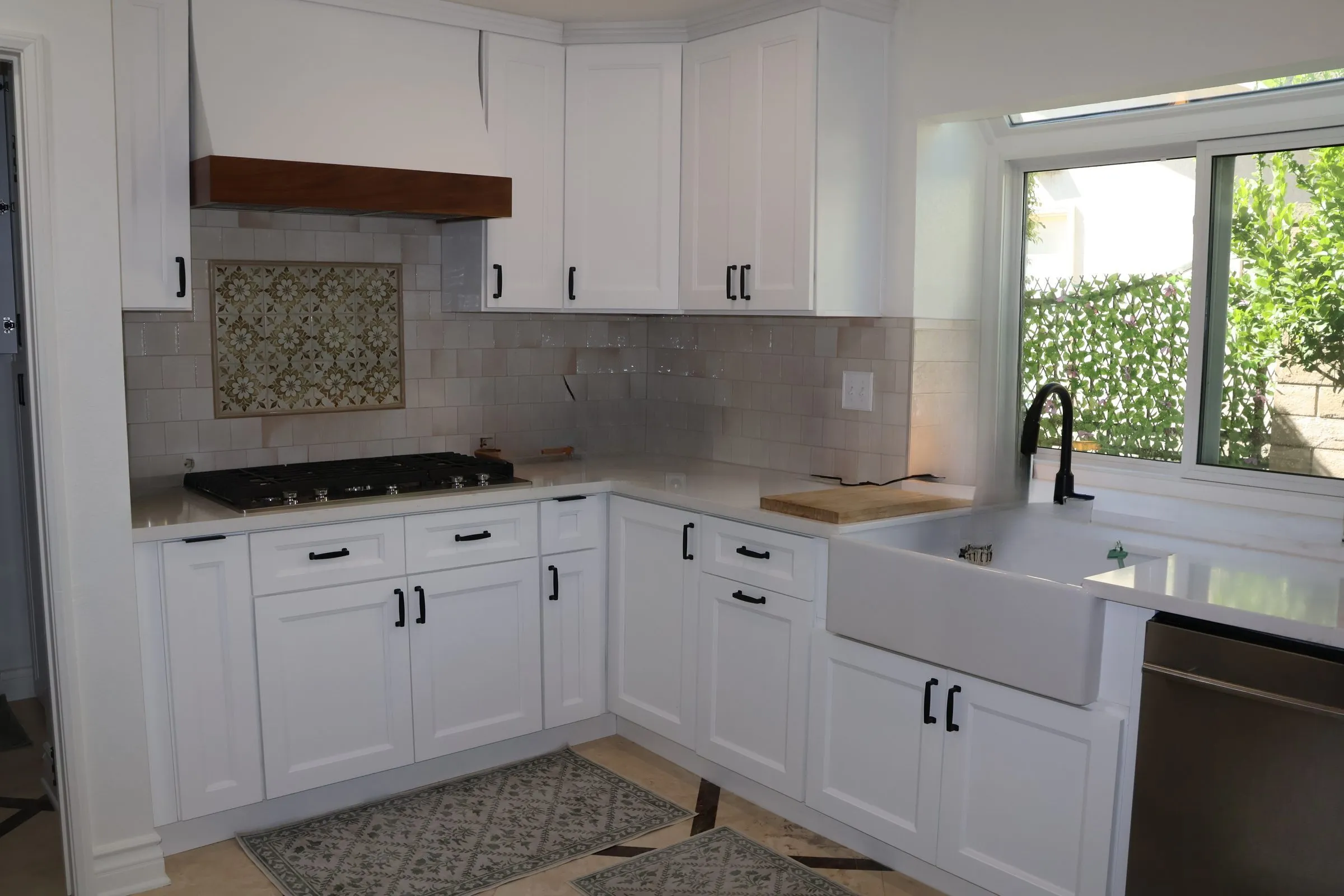 White shaker kitchen with a hand-built wood hood over patterned encaustic tile