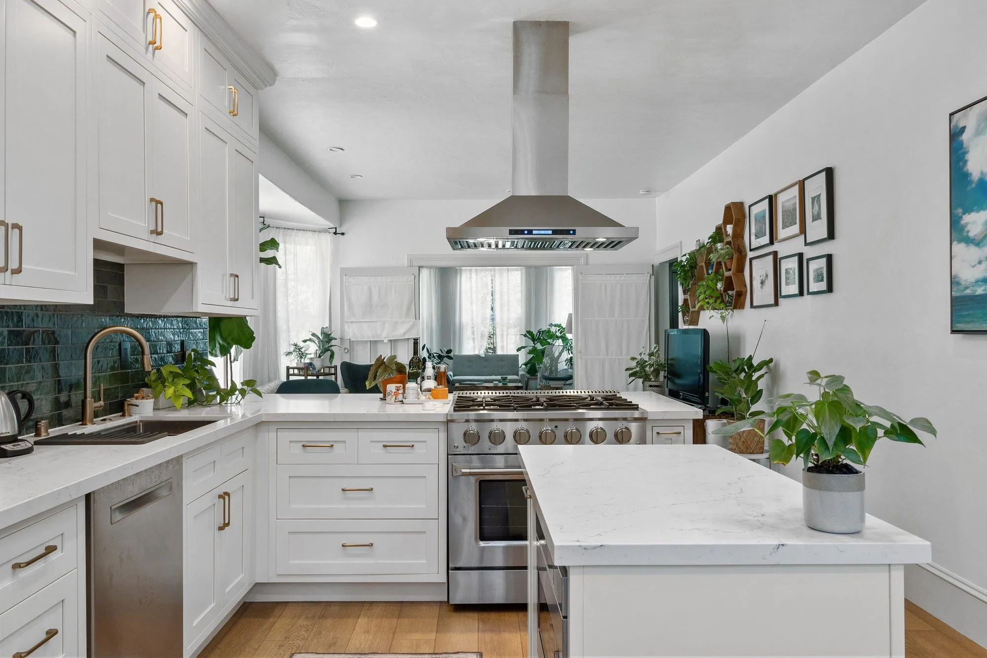 Kitchen after remodel, white shaker cabinetry against a deep teal backsplash with a quartz island