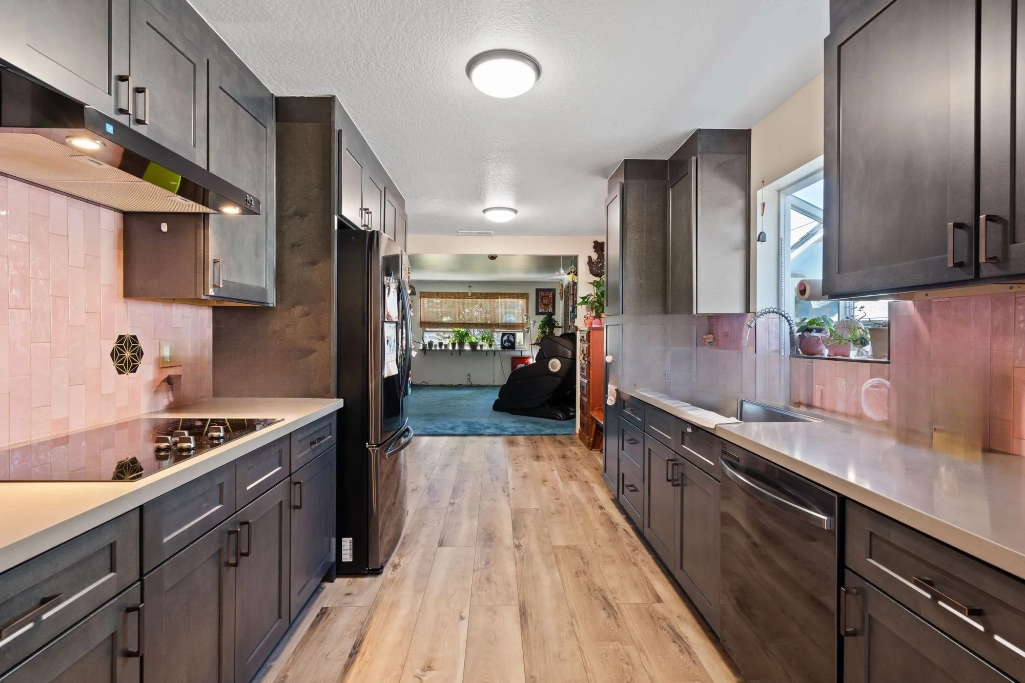 Galley kitchen in dark shaker cabinetry with a blush tile range wall