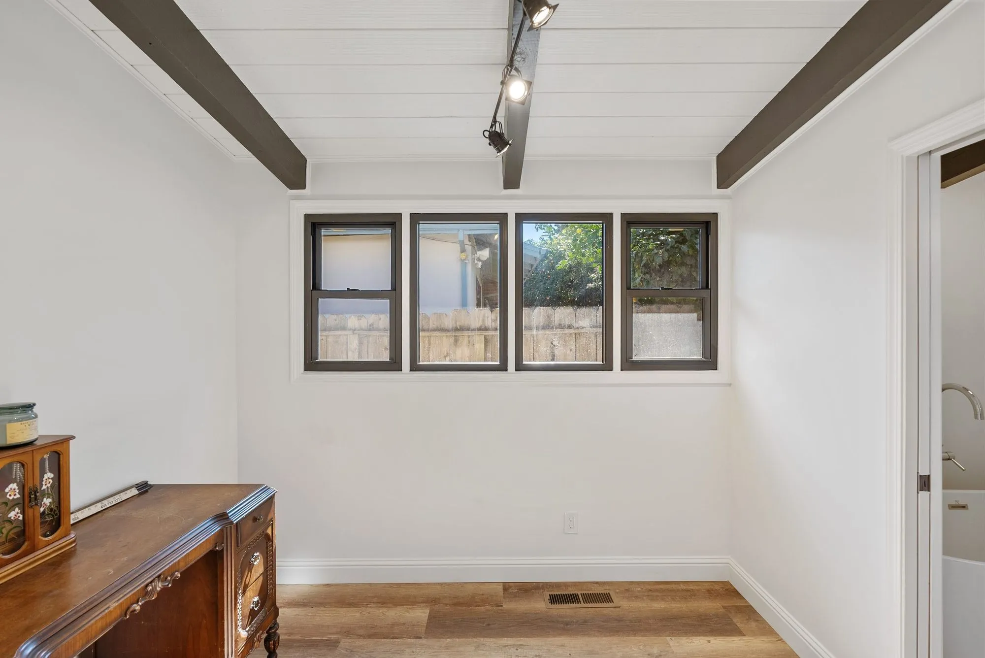 Living space after whole-home remodel, shiplap ceiling with exposed dark beams and light oak plank flooring