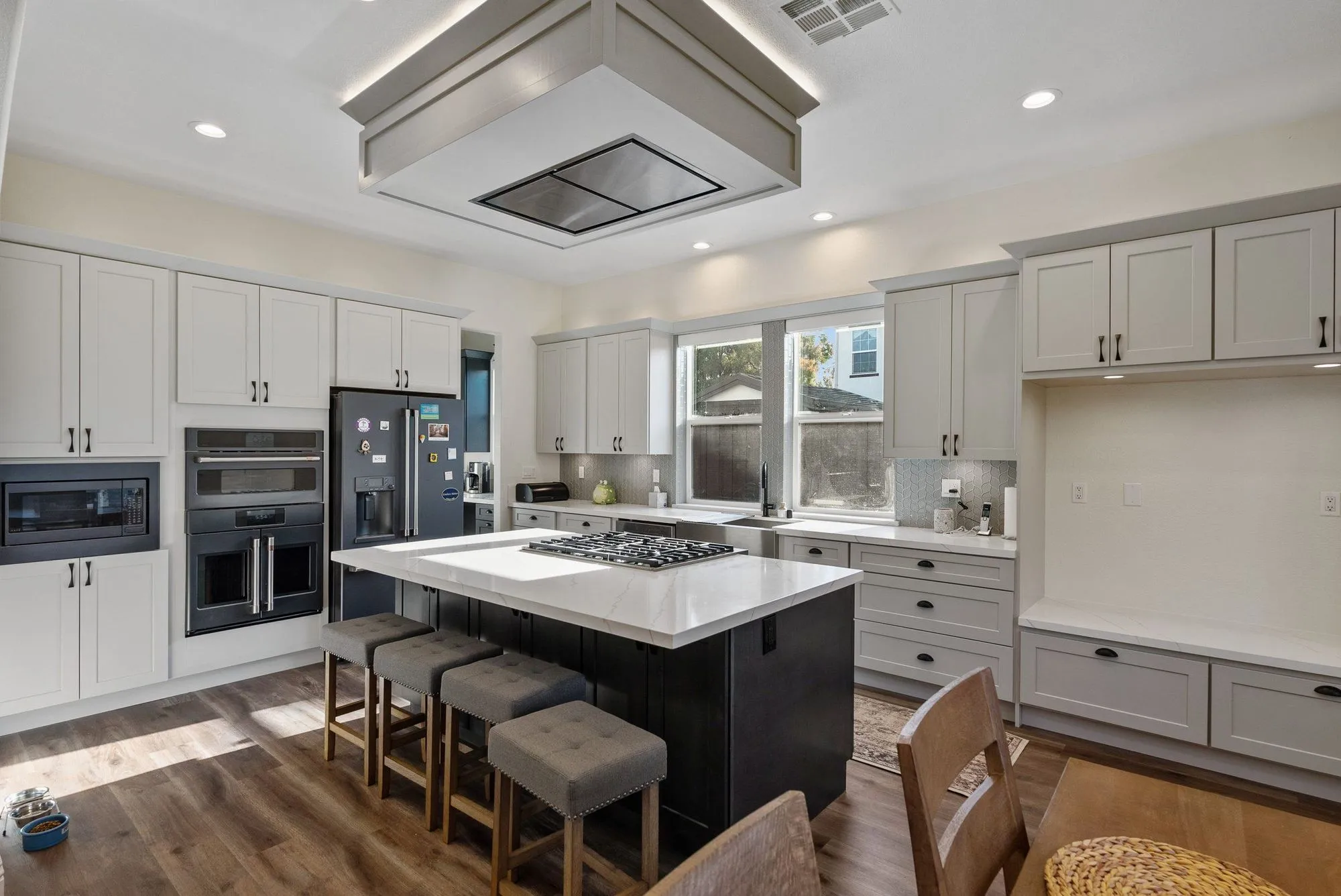 Kitchen after whole-home remodel, white cabinetry with a large island and stacked wall ovens