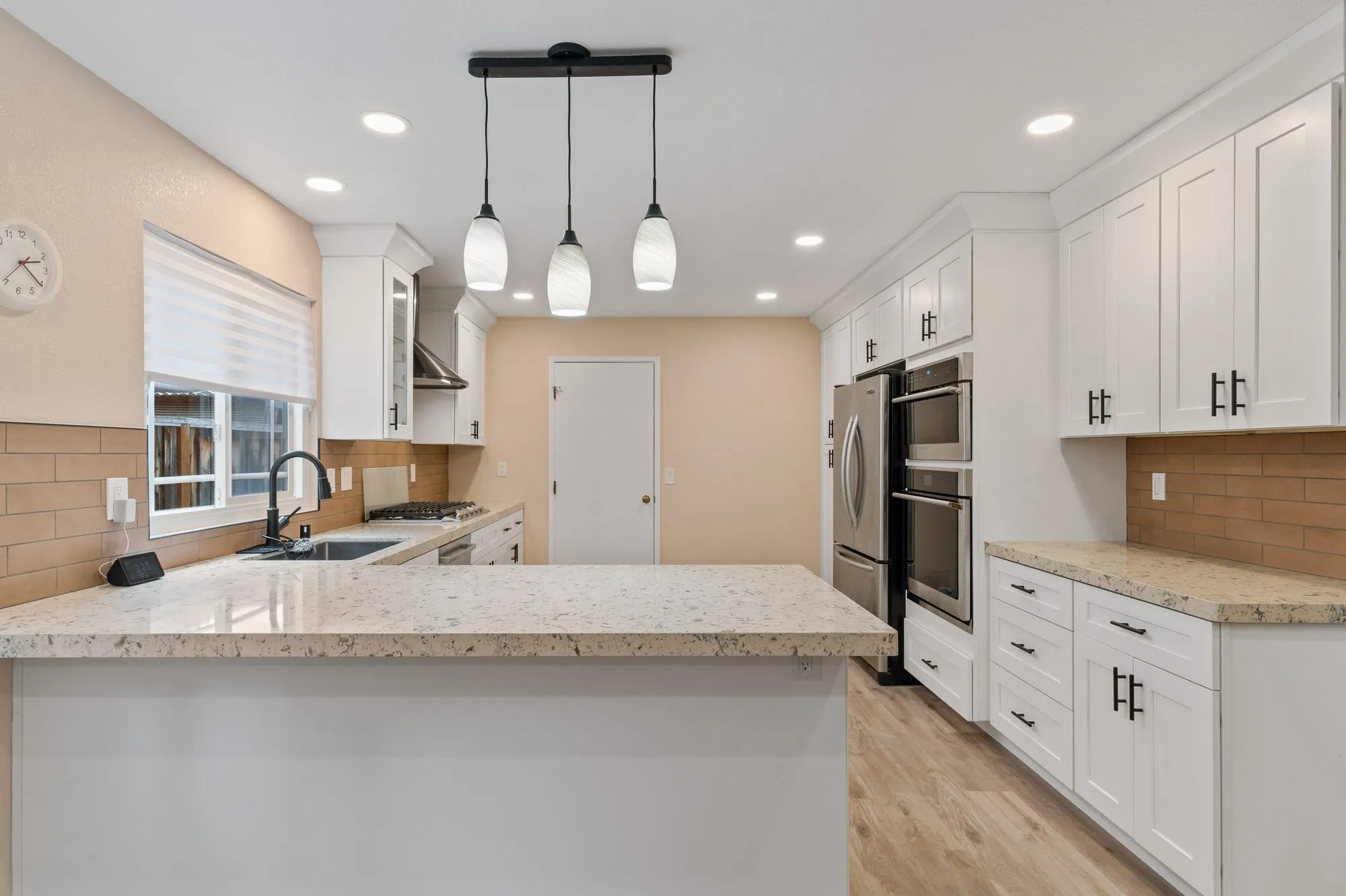 Kitchen after whole-home remodel, white shaker cabinetry with granite counters and tan subway tile backsplash