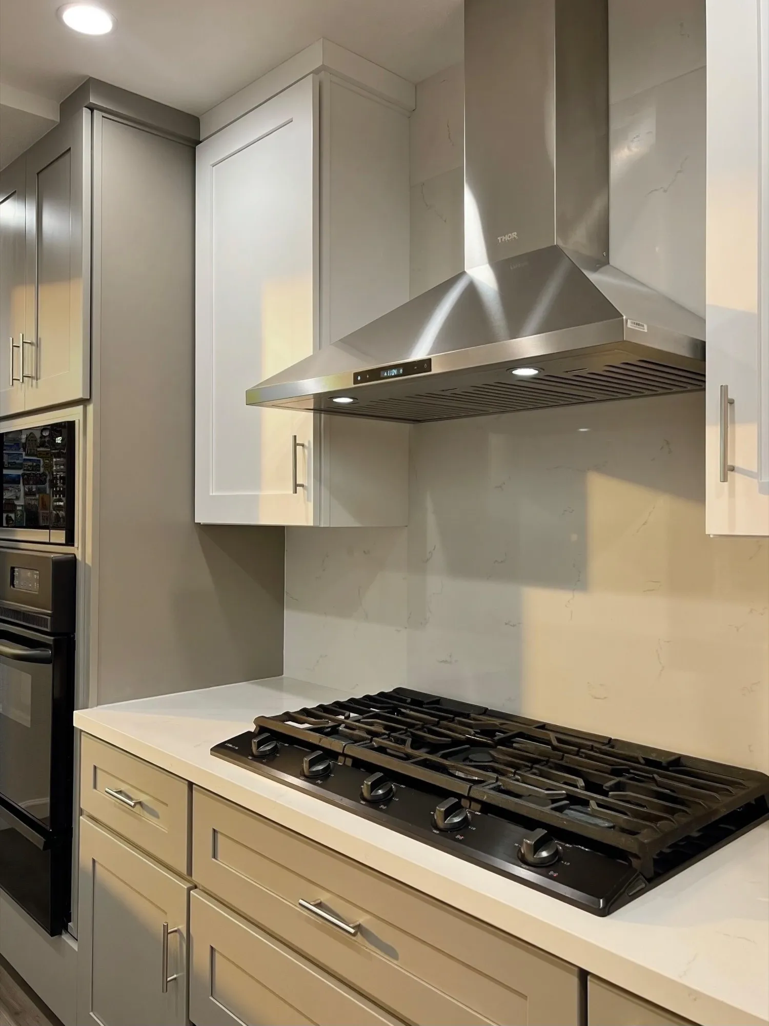 Stainless chimney hood over the gas cooktop, quartz slab behind