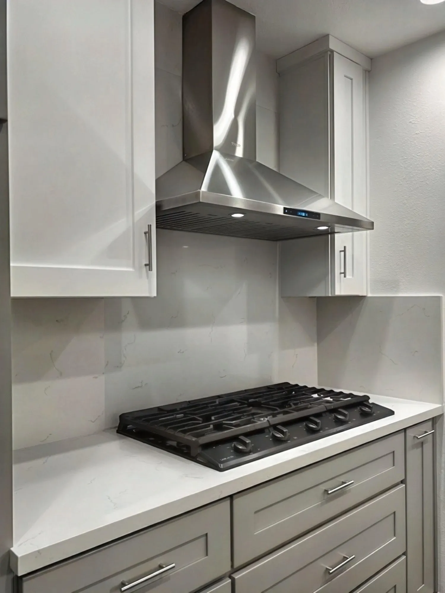 Hood and cooktop straight on, white upper cabinets either side