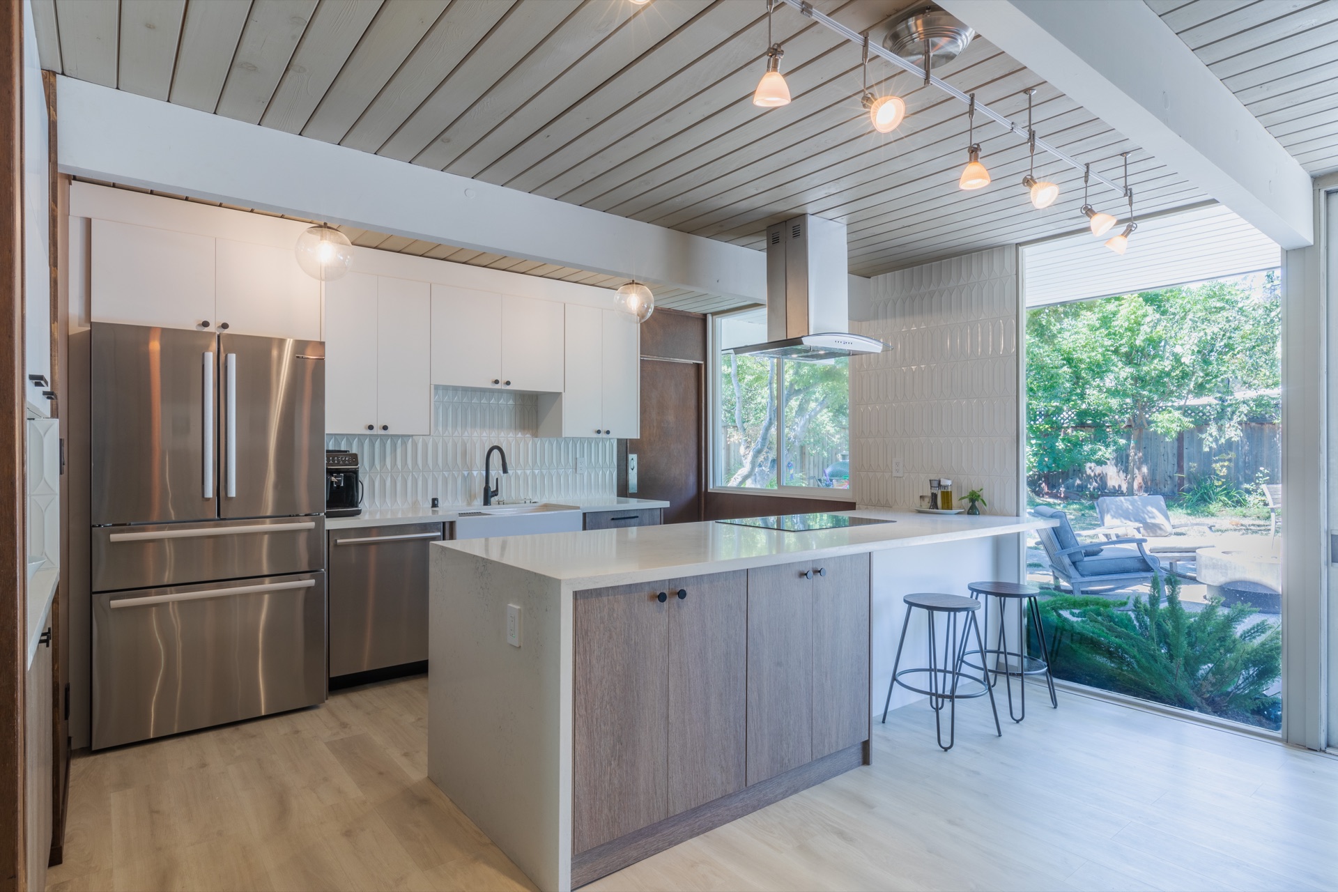 Mid-century modern kitchen with wood cabinetry, patterned tile backsplash, and sliding doors to garden
