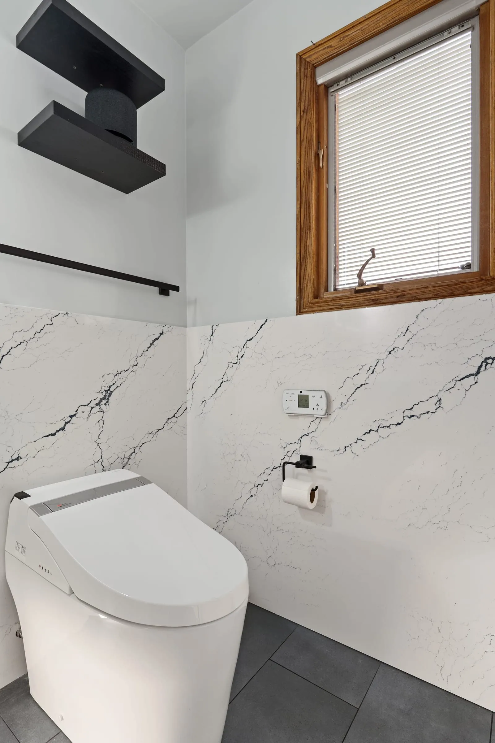 Marble-look slab wall with a matte black towel bar