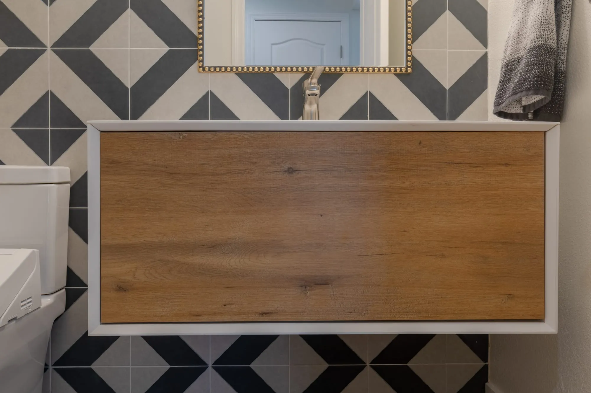 Floating oak vanity against the geometric tile