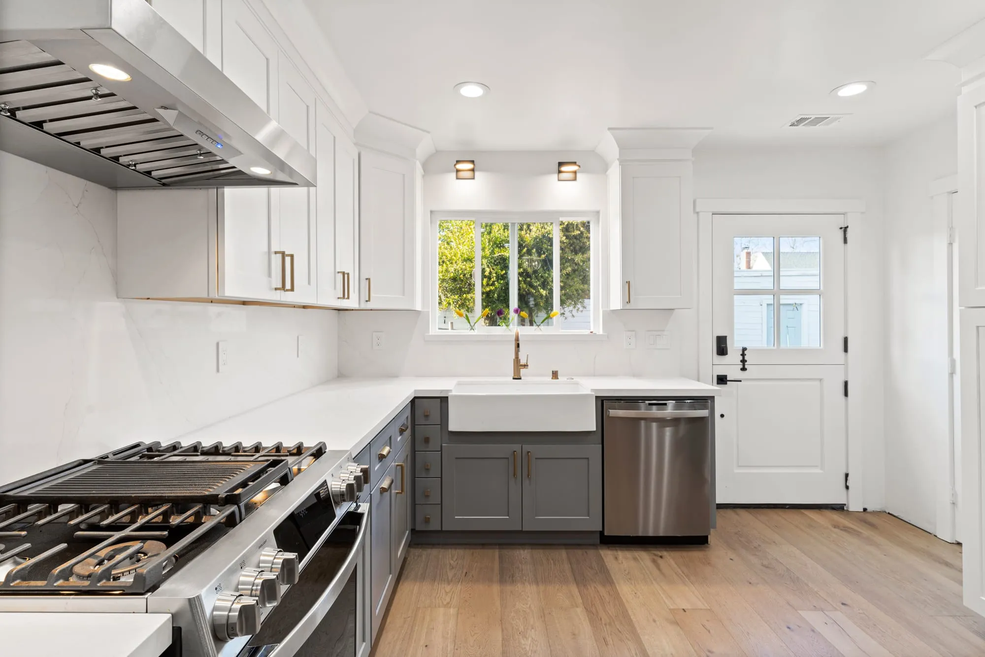 Range under a stainless hood between grey cabinets