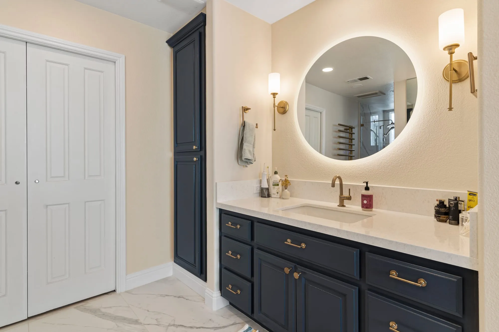 Round backlit mirror above the navy vanity