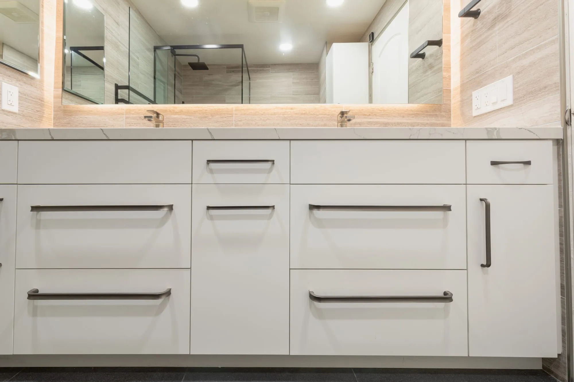White shaker vanity with deep drawers and long matte black pulls under a veined quartz counter