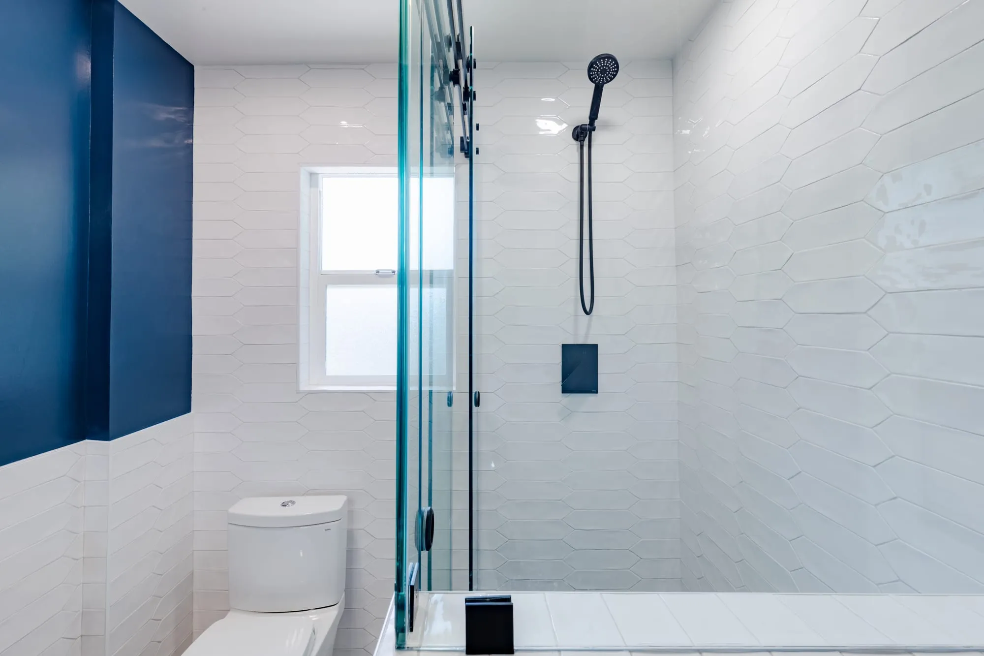 Shower with a hand shower against textured white tile