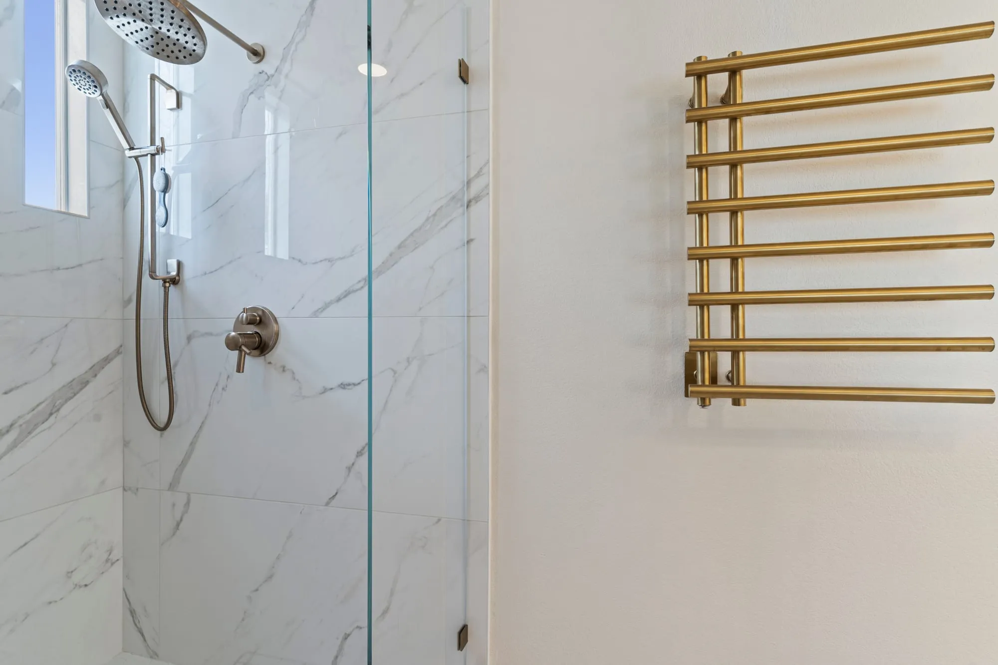 Shower with a brass towel warmer alongside