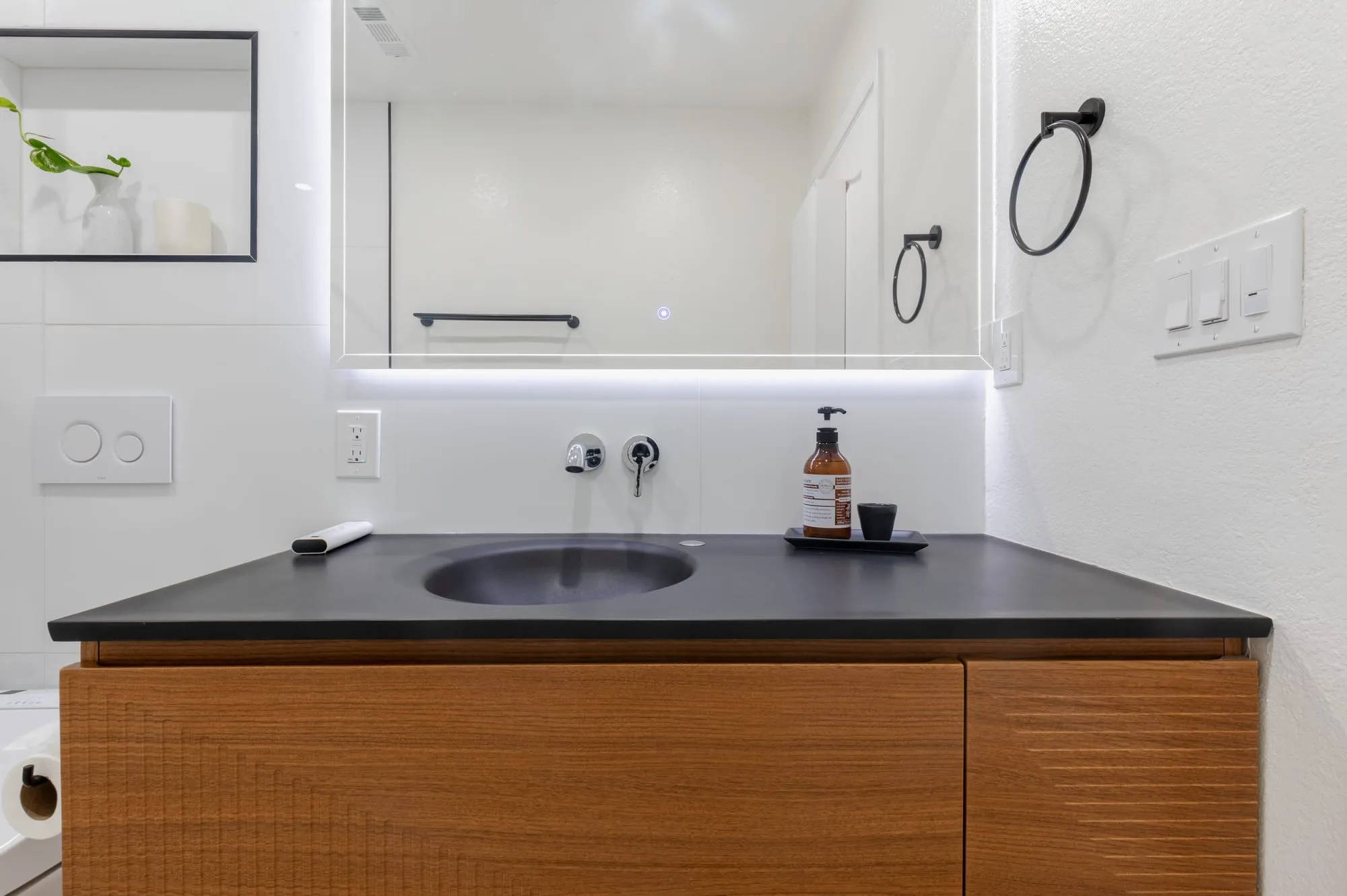 Stone basin and wall-mounted tap on the dark counter