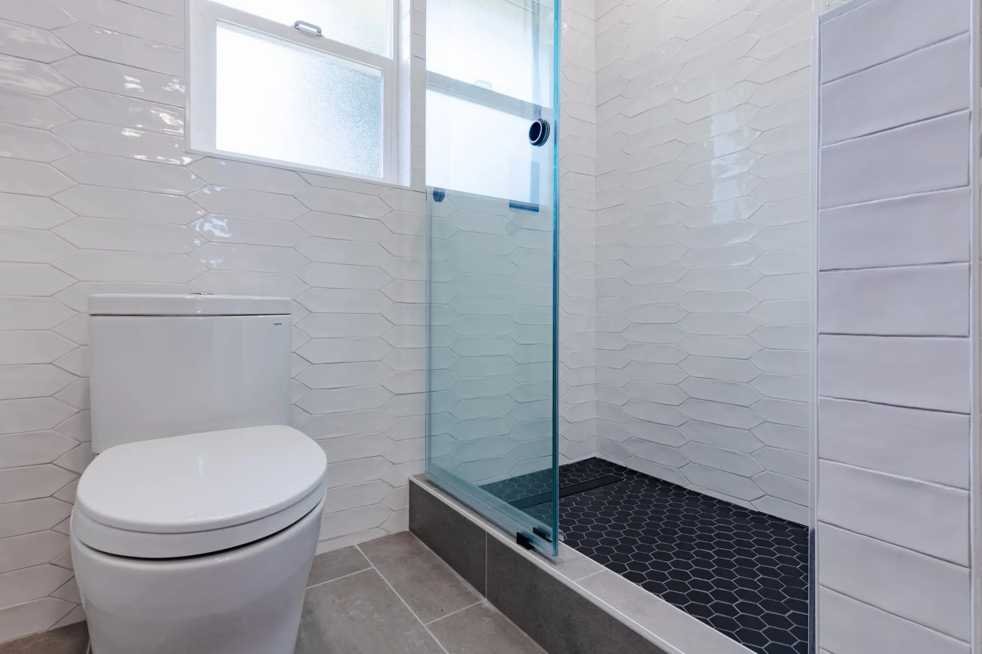 Textured white tile lining the shower behind glass