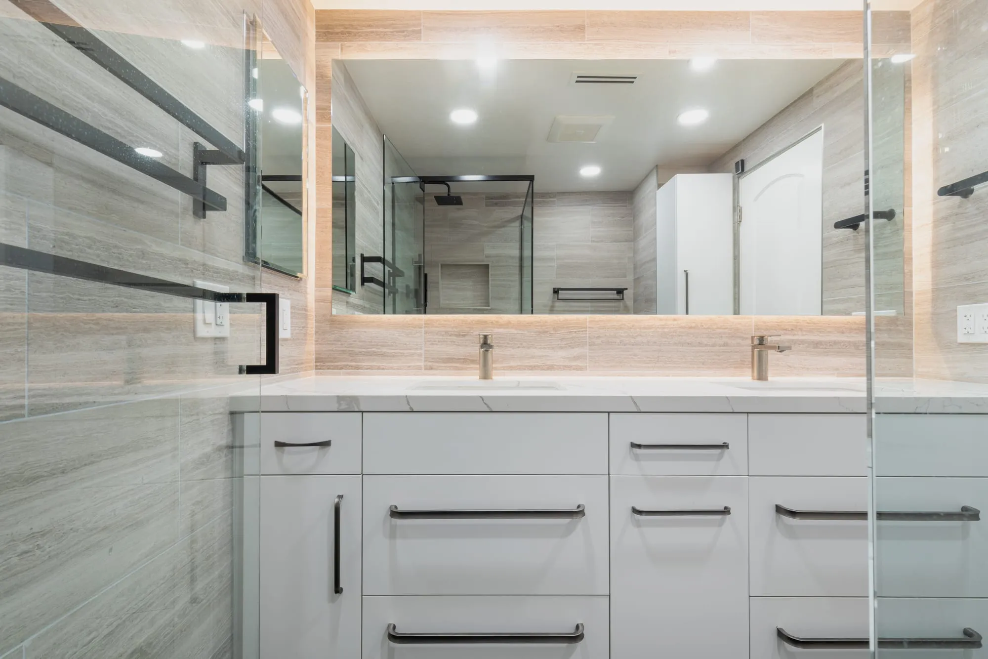Two undermount basins set into a veined quartz counter with matte black mixers