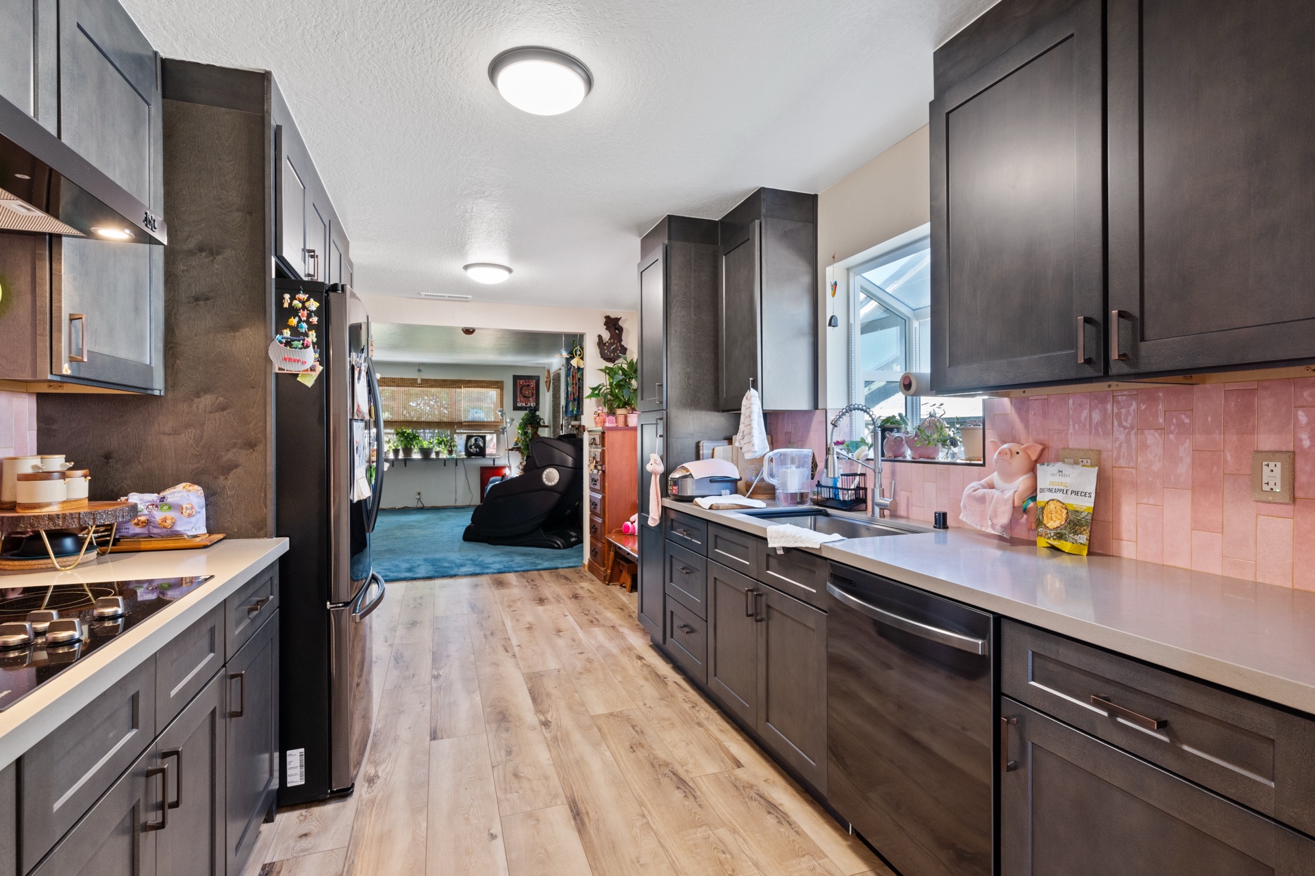 Dark-wood galley kitchen with island cooktop and view through to family room