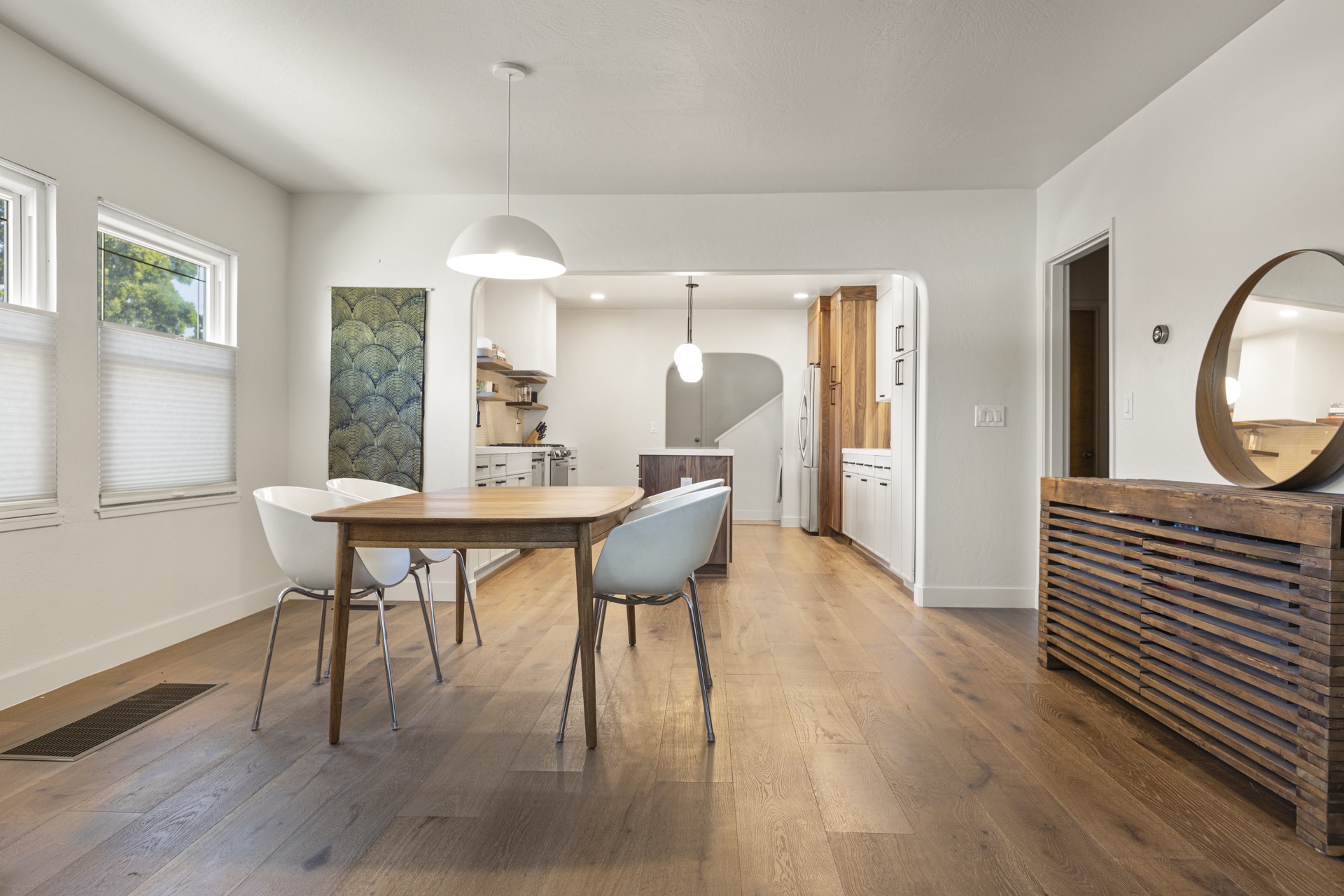 Modern dining room with wood table, pendant lighting, and open kitchen beyond