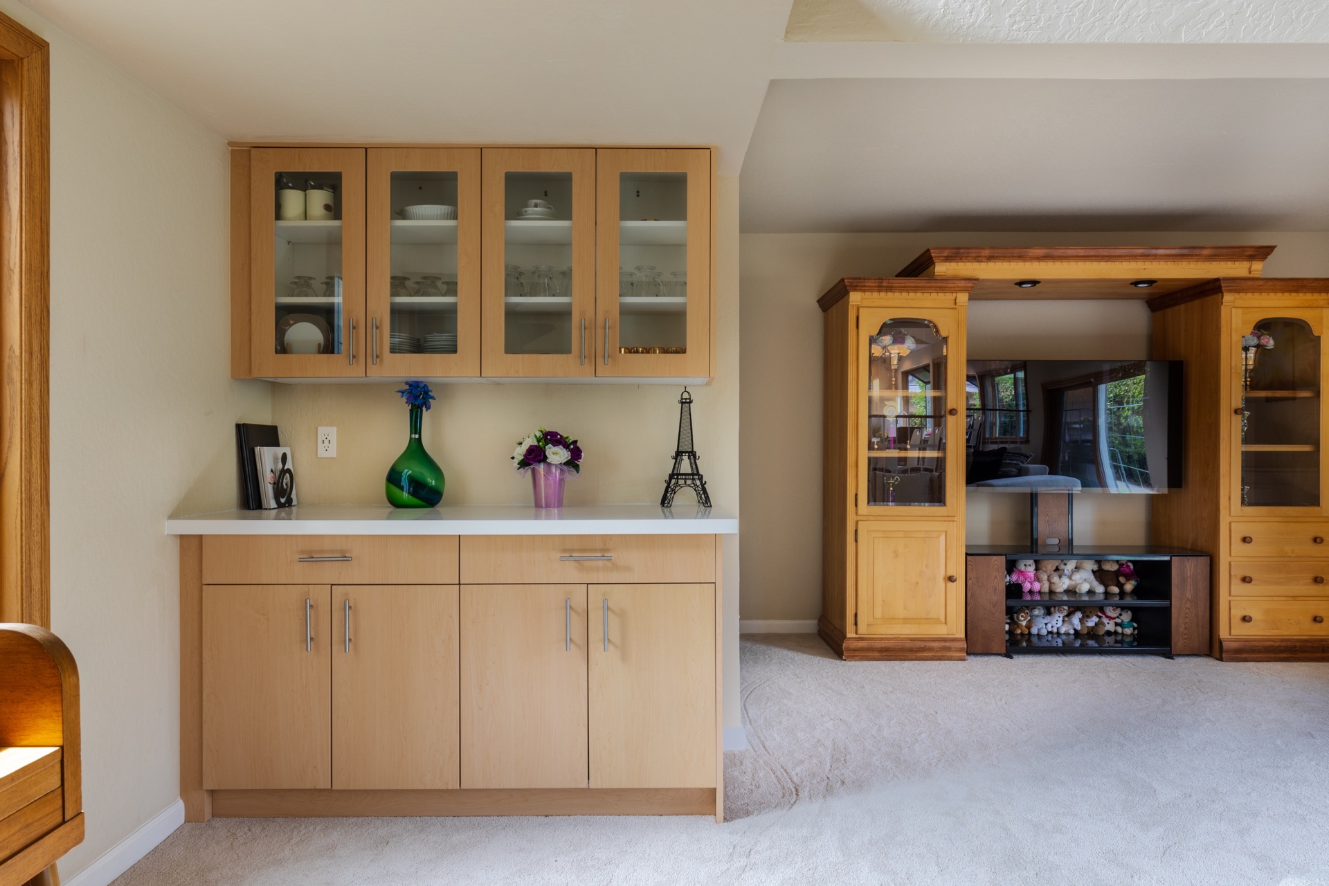 Built-in dining sideboard with glass-front display cabinets and adjacent living area