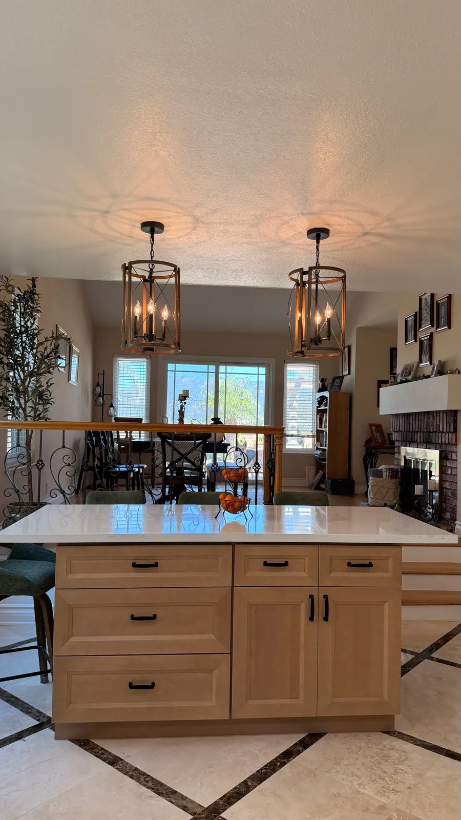 Natural-wood island under a pair of iron lantern pendants against white shaker cabinetry